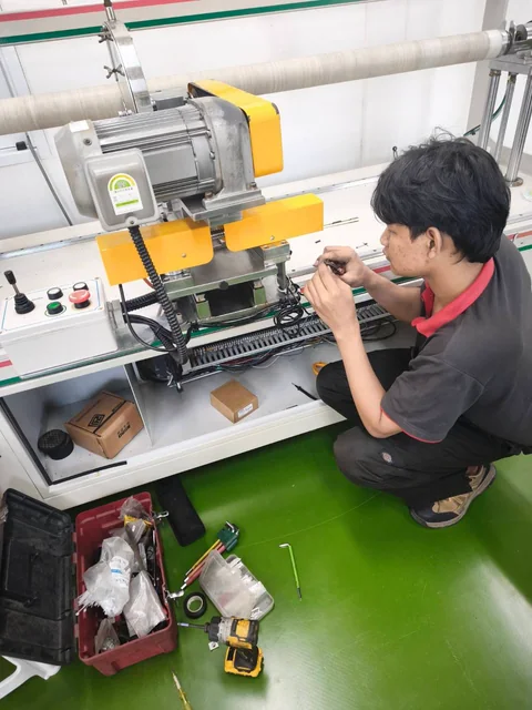 ช่างทำงานกับสายไฟบริเวณเครื่องจักรที่มีมอเตอร์และชุดปุ่มควบคุม